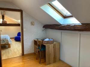 a attic room with a skylight and a table and a bed at Sous le bon Toit in Belley