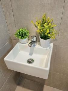 a white sink with two plants on top of it at Zizi Homey Cemara Asri Triple Room 202 in Medan