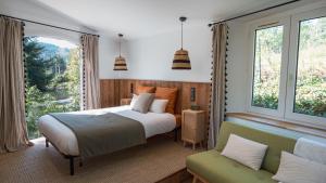 1 dormitorio con cama, sofá y ventanas en Le Pavillon - Les Lodges de Praly en Les Ollières-sur-Eyrieux