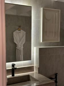 a bathroom mirror with a white robe on a hanger at شاليه pali villa in Buraydah