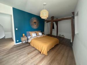 ein Schlafzimmer mit einem Bett und einer blauen Wand in der Unterkunft Appartement cœur de ville in La Flèche