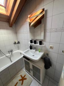 La salle de bains est pourvue d'un lavabo et d'une baignoire. dans l'établissement Gemütliche Dachgeschosswohnung mit Balkon, à Ainring