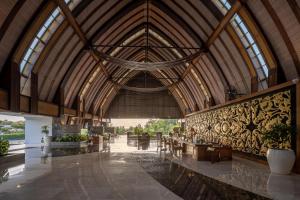 un grand bâtiment avec un plafond en bois et un hall dans l'établissement MERUSAKA Nusa Dua, à Nusa Dua