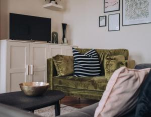 a living room with a green couch and a television at Pebble View - Central Cosy with Sea-Views in Weymouth