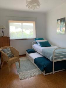 a bedroom with two beds and a chair and a window at GuestReady - Pleasant Retreat in Moledo in Moledo