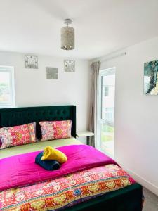 a bedroom with a pink bed with a yellow blanket at Modern Flat with En-suite and Free Parking in Chatham