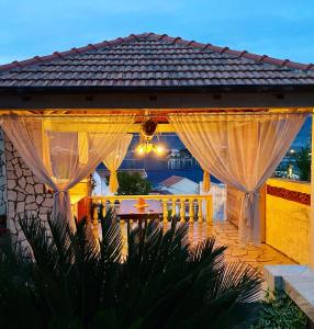 a gazebo with curtains and a table at INO Apartments in Tivat