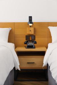 台中的住宿－新藍天旅棧，一张睡床,床之间有床头柜上的电话