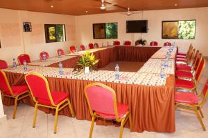 a long table in a room with red chairs at Pebbles guesthouse in Diani beach road in Ukunda