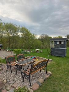 a picnic table and two benches in a yard at Domek na wsi- Przezmark pod Elblagiem in Elblag