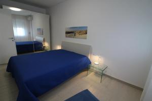 a bedroom with a blue bed and a glass table at Appartamenti Luna in Lignano Sabbiadoro