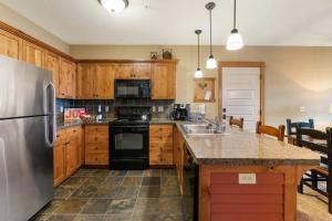 a kitchen with wooden cabinets and a stainless steel refrigerator at Silver Mountain Resort in Kellogg