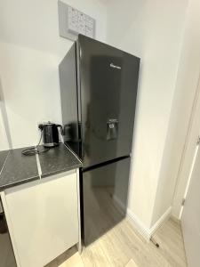 a stainless steel refrigerator in a kitchen with a counter at 2 BED 1 BATH LUXURY STAY APARTMENT 20 Mins drive to Central London 10 Min Drive to Wembley Stadium Free Parking in Golders Green