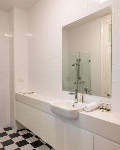 a white bathroom with a sink and a mirror at Modern 1-Bed Studio near Tramsheds in Sydney