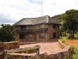 una vieja casa de piedra en un campo con una valla en Masungulo Lodge, en Modimolle