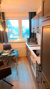 a kitchen with a counter and a table and two windows at Das kleine Penthouse mit Kamin in Bad Sachsa