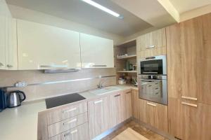 a kitchen with wooden cabinets and a sink and a microwave at TAMARI Luxury Villa - Miramare in Pefkohori