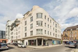 a large white building on a city street with cars at The Aldgate Flat in London