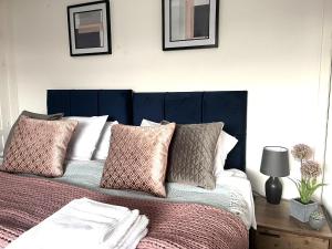 a bedroom with a bed with a blue headboard and pillows at Harrowby Home in Lincolnshire