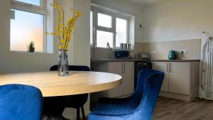 a kitchen with a wooden table and blue chairs at Harrowby Home in Lincolnshire