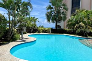 uma piscina com palmeiras e um edifício em Duplex design sea view em Papeete