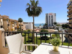 balkon ze stołem, krzesłami i palmą w obiekcie Erisa Terral Apartments w mieście Torremolinos