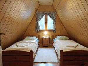 two beds in a attic room with a window at Domki Bieszczady Siedlisko Harenda in Czarna