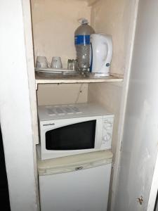 a small kitchen with a microwave on top of a refrigerator at Charis Guesthouse in Hartswater