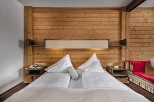 um quarto com uma cama branca e um sofá vermelho em Hotel St. Oswald em Bad Kleinkirchheim