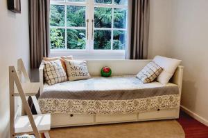 um sofá num quarto com uma janela em Pinehaven Cottage em Upper Hutt