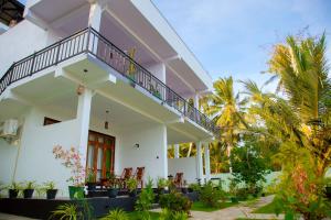 a white house with a balcony and palm trees at My Resort Yala in Tissamaharama