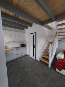 a room with a staircase and a kitchen with white cabinets at Ranczo pod lasem in Witnica