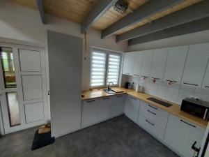 cocina con armarios blancos, fregadero y ventana en Ranczo pod lasem, en Witnica