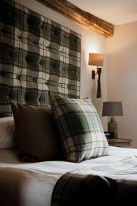 a bedroom with a bed with a plaid headboard and pillows at The White Hart Hotel in Hingham