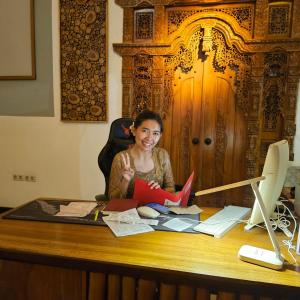 a woman sitting at a desk with a book at Villa Casablanca Surf Keramas in Keramas