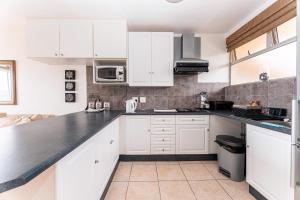 a kitchen with white cabinets and a black counter top at Amazing Sea View Apartment La Ballito in Ballito