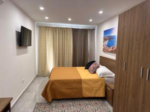 a hotel room with a bed and a television at La Bella Guesthouse in St. Julianʼs