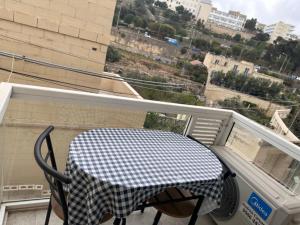 a table and a chair on a balcony with a window at La Bella Guesthouse in St. Julianʼs