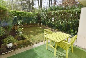 a yellow picnic table and bench in a garden at PALMIER Jardin Disneyland JO Paris 2024 - 4 personnes et bébé in Torcy