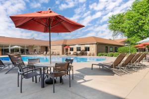 uma mesa com um guarda-chuva vermelho ao lado de uma piscina em Best Western Plus Ramkota Hotel em Sioux Falls