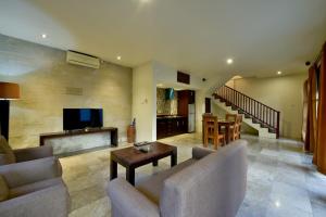 a living room with a couch and a tv and a table at The Khayangan Dreams Villa Umalas in Canggu