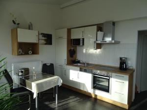 una cocina con armarios blancos y una mesa. en Ferienapartment Birkenhain en Wettringen