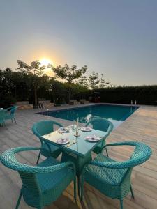 een tafel met vier stoelen naast een zwembad bij Luxurious Farmhouse with Pool outside Delhi in Noida