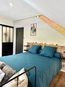 ein Schlafzimmer mit einem großen Bett mit blauen Kissen in der Unterkunft studio au cœur de la vannerie in Fayl-Billot