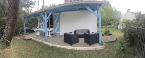 un cenador con un banco y una silla en un patio en L’Albizia, en La Tranche-sur-Mer