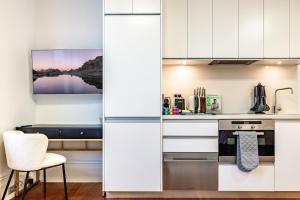 a kitchen with white cabinets and a table and a chair at Stylish Studio near the City Centre in Sydney