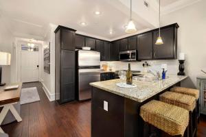 a kitchen with black cabinets and a kitchen island with bar stools at The Metro - DTWN Fay Condo - 2 Blocks to Dickson St in Fayetteville