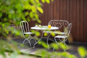 a table and chairs on a deck with a drink at Isäntä in La Ferté-Saint-Aubin