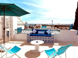 eine Terrasse mit Stühlen, einem Tisch und einem Sonnenschirm in der Unterkunft Cosy S3 Apartment in Sidi Bou Said Village in Sidi Bou Saïd