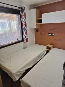 two beds in a room with a window at Mobil home 3 chambres avec vue sur l'étang - 4* in Canet-en-Roussillon